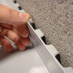 A contractor in Essex installing a perimeter drain tile system during a sump pump installation.