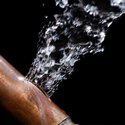 A bursting copper pipe in Wilmington, with water gushing out.