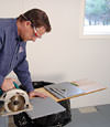 installing a waterproof vapor barrier on a basement floor to prepare for basement carpeting in a Wilmington home