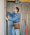 Insulated basement wall panels being placed against a concrete foundation wall in Dundalk